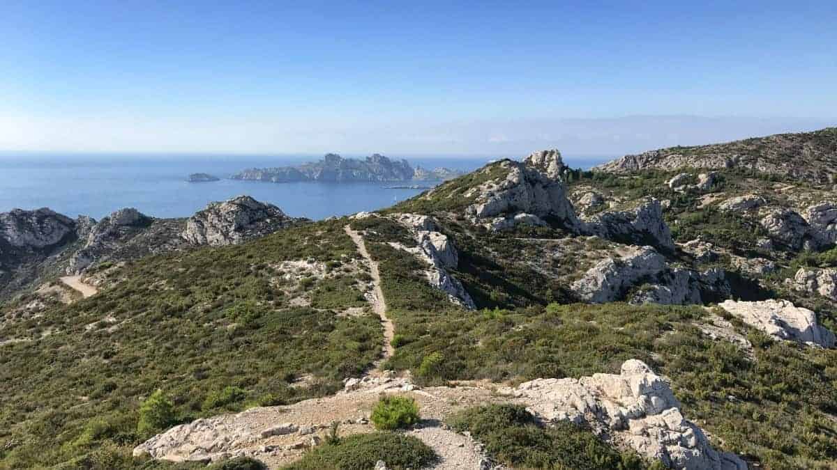 Küstenwanderweg Marseille Etappe 5 schroffe Felsen sattes Grün blauer Himmel und das Meer im Parc National des Calanques